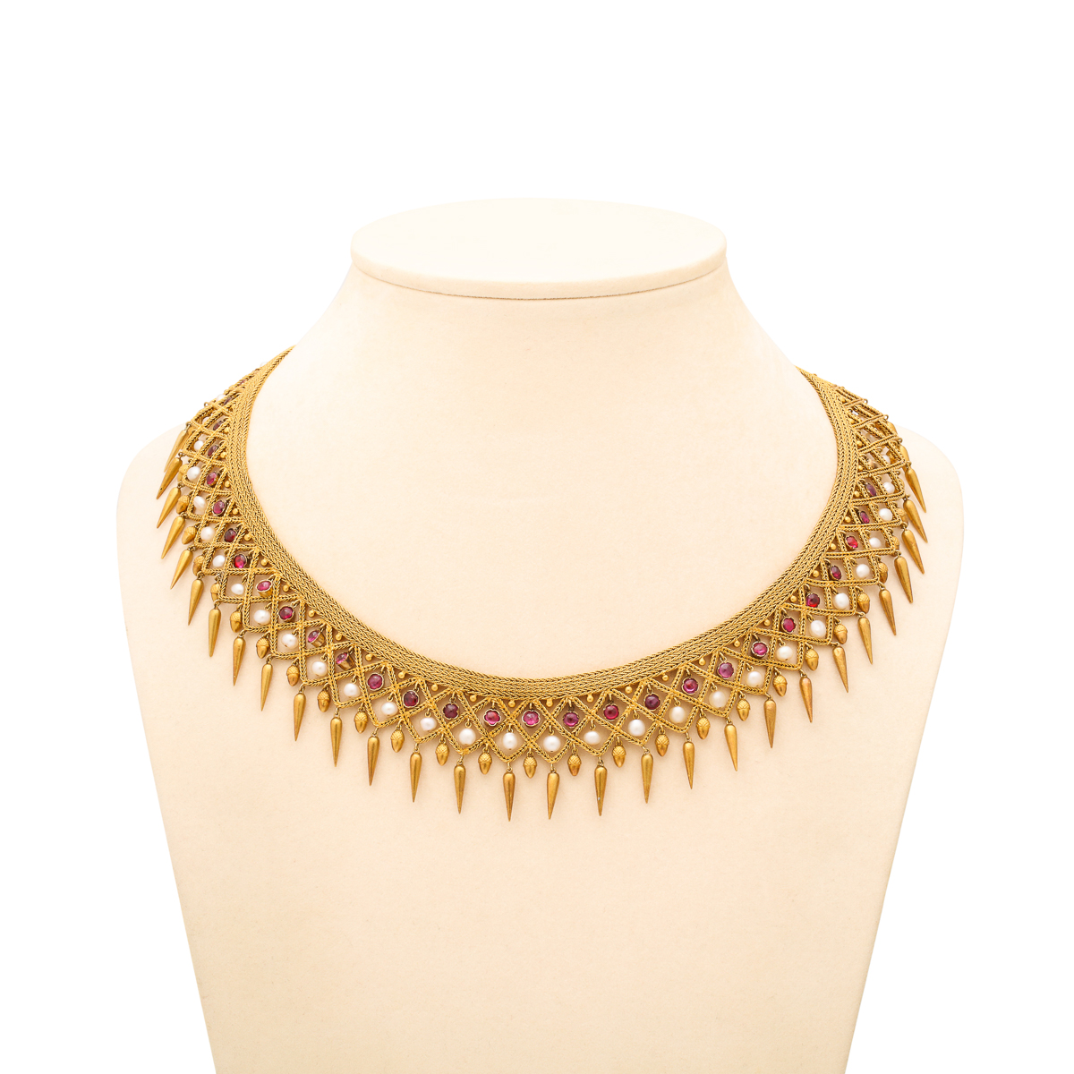 front view of gold fringe necklace set with rubies and natural pearls, pictured on beige neck block