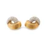 side view of gold and pave diamond clip earrings in a swirl design