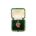 red, white, and green enameled twisted heart pendant set with a natural pearl in a green box