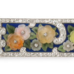 Detail view of carved multicolor hardstone floral brooch with blue enamel background and diamond border