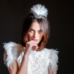model wearing white feather dress and a diamond angel wing tiara set with a feather