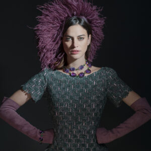 Model wearing green dress, purple gloves and feathered hat with amethyst and chrysoprase necklace and bracelet