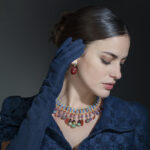 Model wearing blue dress and gloves and Egyptian Revival earrings and necklace