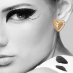 Model wearing gold heart shaped earrings with diamonds by Cartier